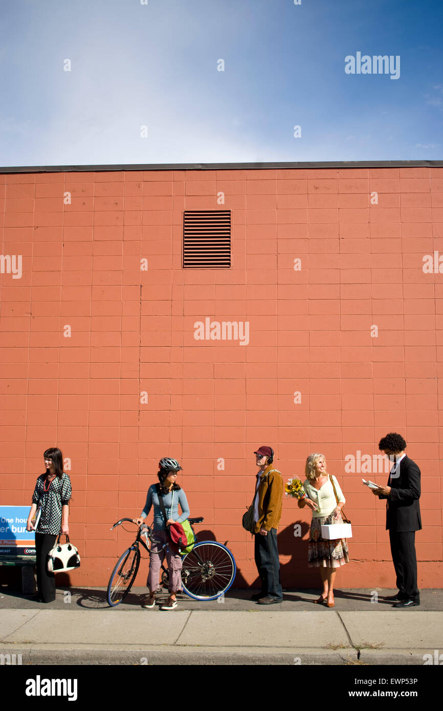 Fünf Erwachsene warten auf den Bus in einem städtischen Gebiet Stockfoto