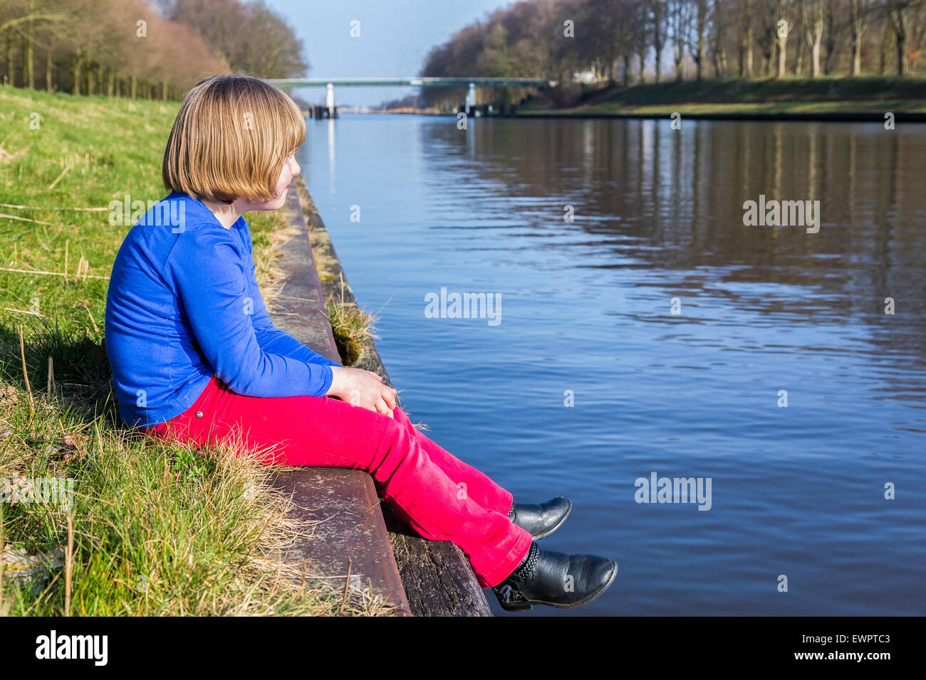Junges Mädchen sitzen am Ufer des Flusses die Aussicht genießen Stockfoto