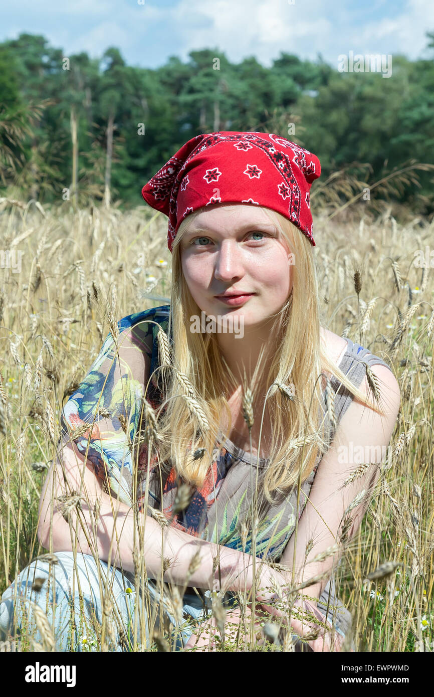 Blonde kaukasische Teenager-Mädchen sitzen im Kornfeld tragen rote Taschentuch Stockfoto