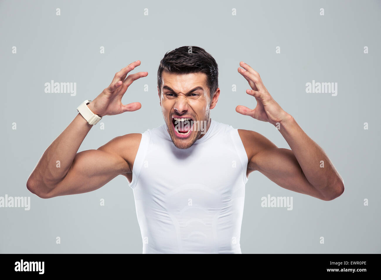 Portrait von wütenden Fitness Mann schreien über grauen Hintergrund Stockfoto