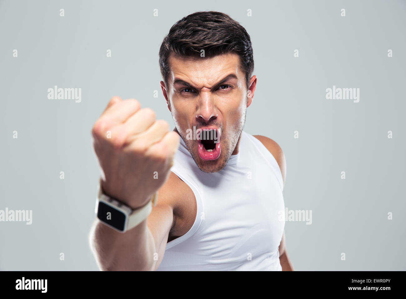 Verärgerter Mann schreien und zeigt Faust auf grauem Hintergrund Stockfoto
