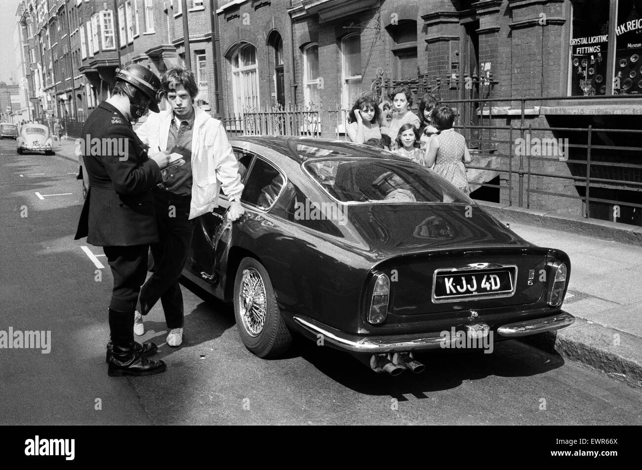 Rolling Stones: 28. August 1966 Mick Jaggers nachtblauen Aston Martin DB6 Kollision mit einem Fahrzeug von Kraft Foods in großen Titchfield Street, London beteiligt war. Jaggers Freundin Chrissie Shrimpton schaut zu, wie Mick seine Angaben durch ein p genommen hat Stockfoto
