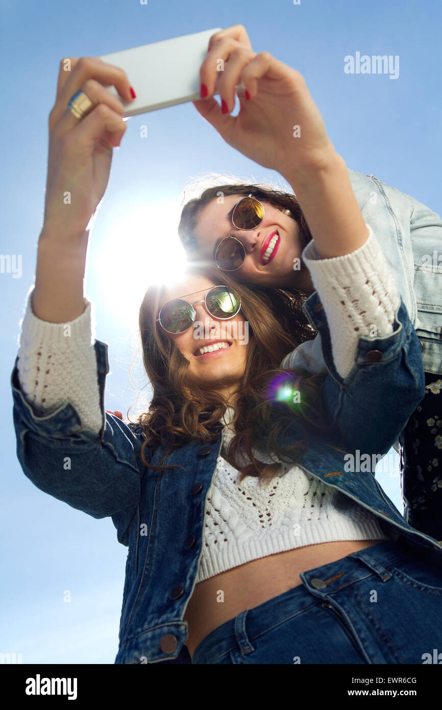 Zwei Mädchen mit Sonnenbrille fotografieren mit einem smartphone Stockfoto