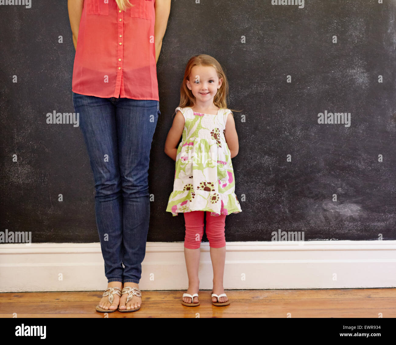Kleines Mädchen mit süßen Lächeln stehen mit ihrer Mutter. Mutter ist auf dem Bild mit Fokus auf kleine Mädchen Blick auf Cam beschnitten. Stockfoto