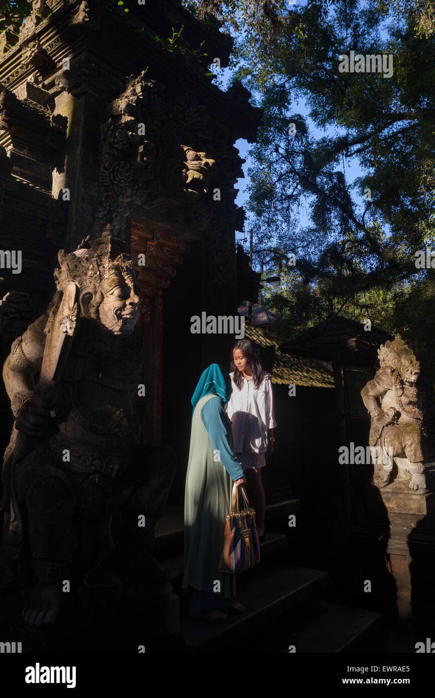 Inländische Touristen chatten am Tirta Empul Tempel Tor mit dvarapala Tor Wächter Skulpturen in Tirta, Bali, Indonesien dekoriert.. Stockfoto