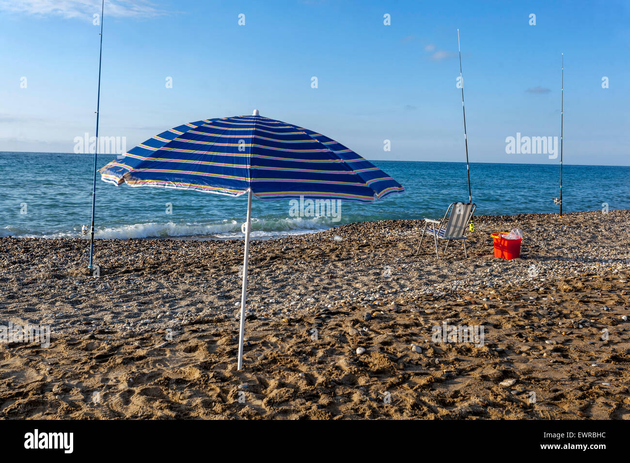 Sonnenschirm am leeren Strand mit Angelruten, Rethymno, Kreta, Griechenland Stockfoto