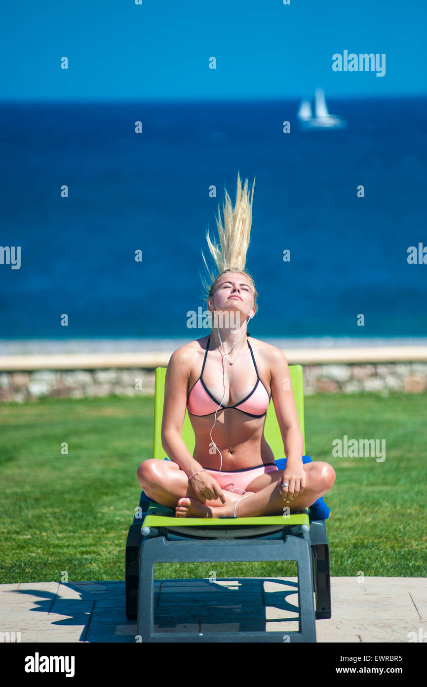 Eine Mädchen zum Sonnenbaden und anhören von Musik auf ihrem MP3-Player wirft den Kopf zurück um ihre langen Haare, die aussehen wie ein Mohican. Stockfoto