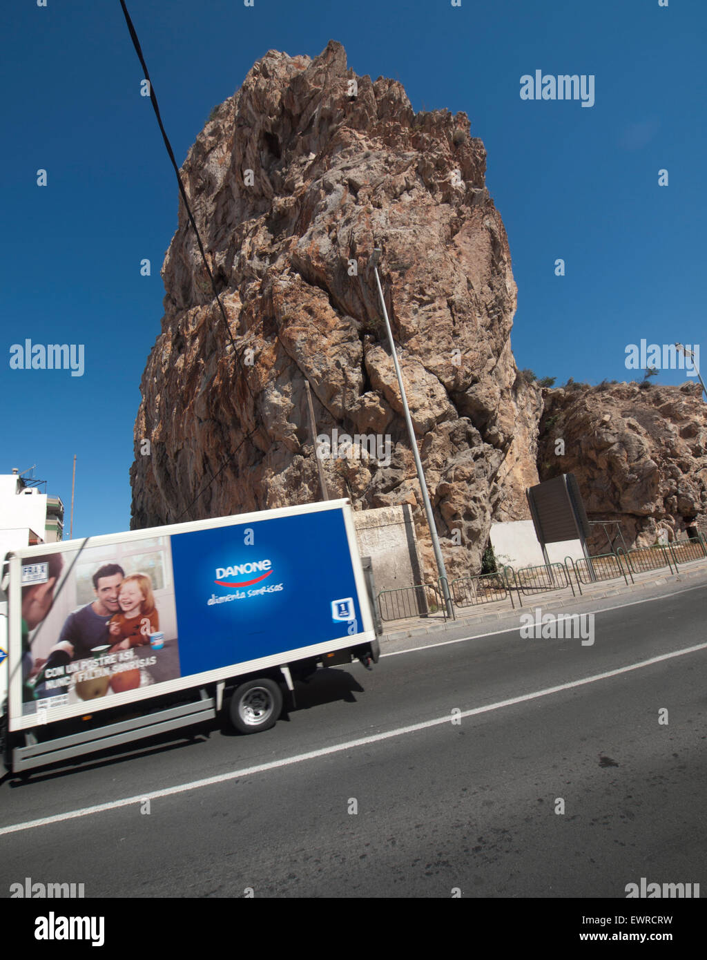 Ein LKW rast vorbei an einem großen Felsen auf einer Straße in Spanien Stockfoto