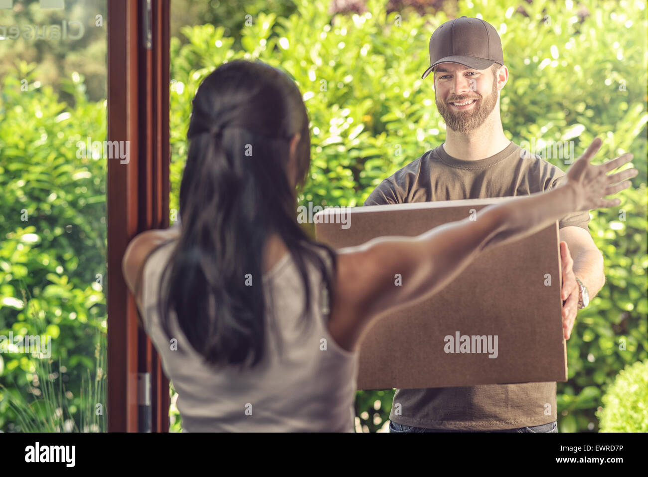 Übernahme eines großen Grundstücks hält seine Arme, der freundlich lächelnden Bote, wie er es, Blick vom übergibt Frau Stockfoto