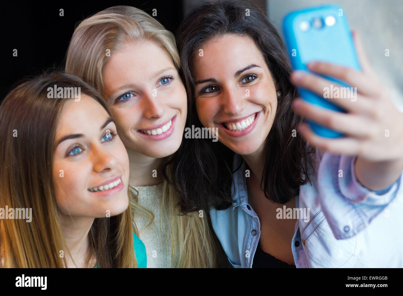 Indoor-Porträt von drei Freunden fotografieren mit einem smartphone Stockfoto