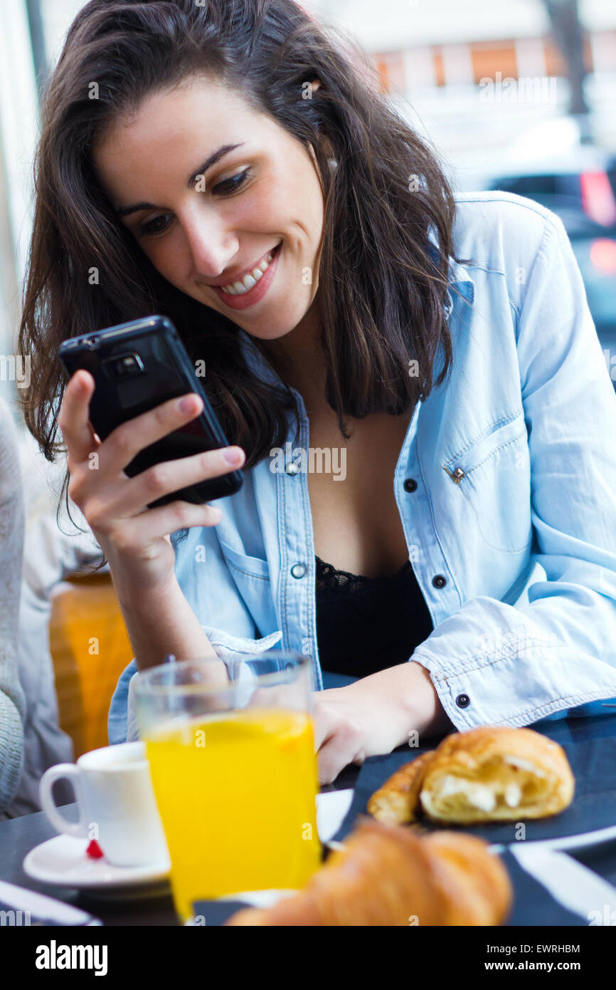 Süße junge Frau, die im Chat mit ihrem Smartphone im Coffee shop Stockfoto