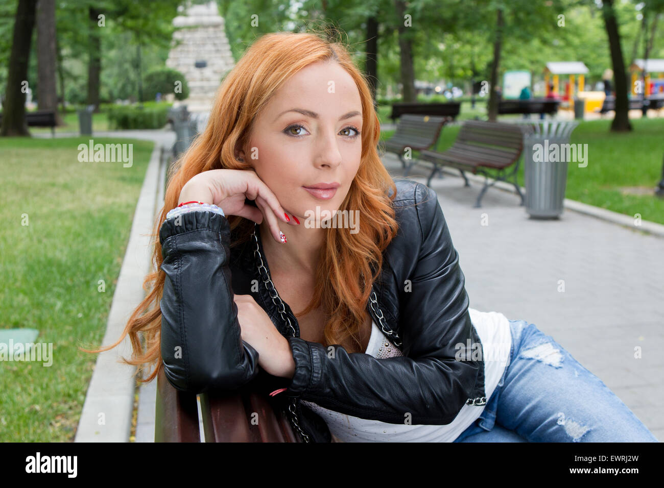 Schöne blonde Frau sitzt auf der Bank im Park im freien Stockfoto