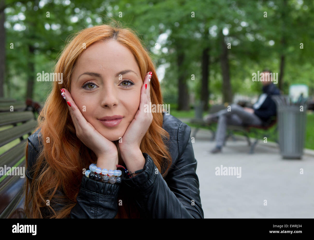 Schöne blonde Frau sitzt auf der Bank im Park im freien Stockfoto