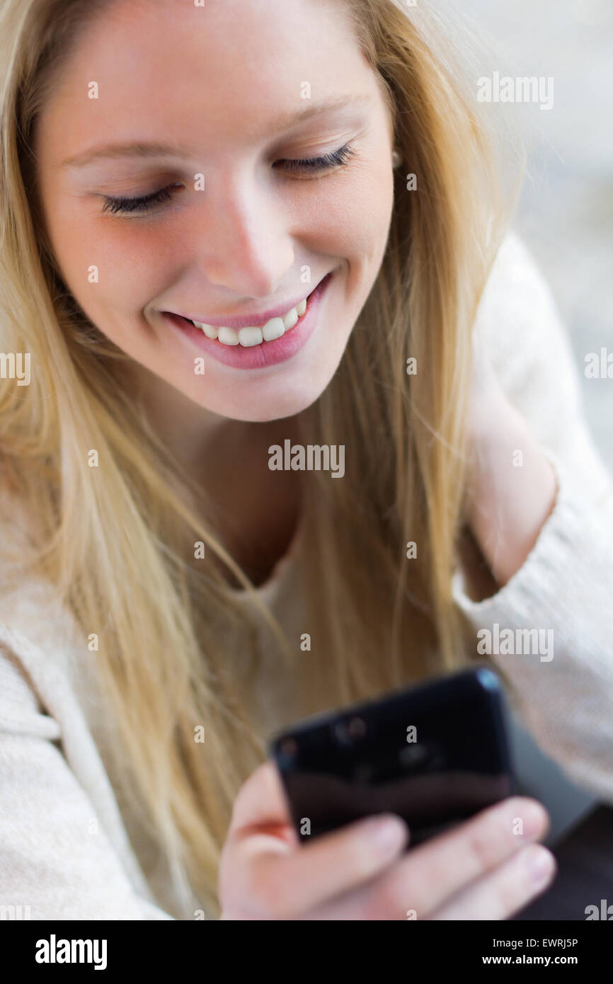 Süße junge Frau, die im Chat mit ihrem Smartphone im Coffee shop Stockfoto