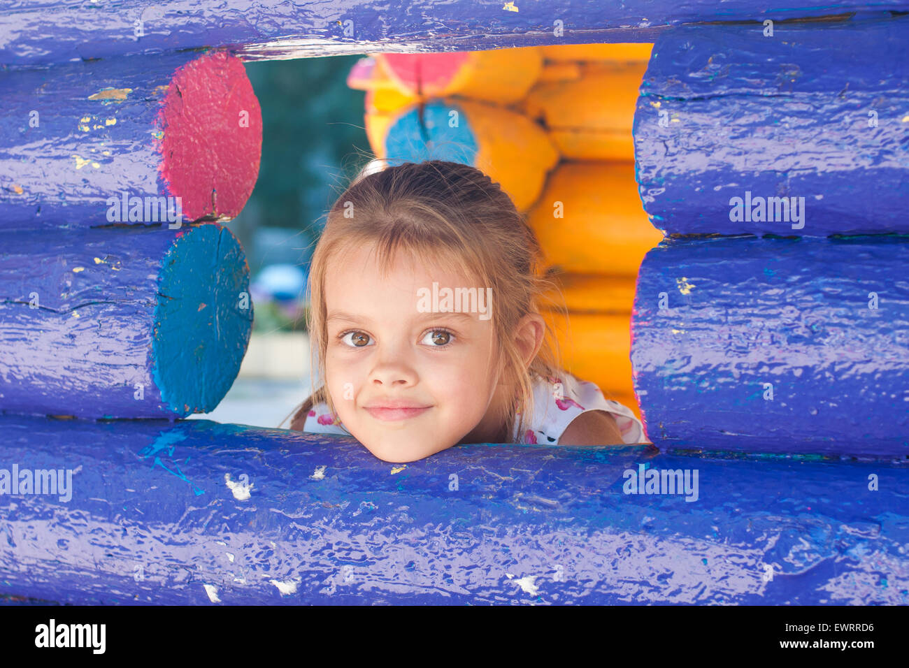 Fünfjährigen Mädchen spielen auf dem Spielplatz schaut aus einem Holz-Fenster Stockfoto