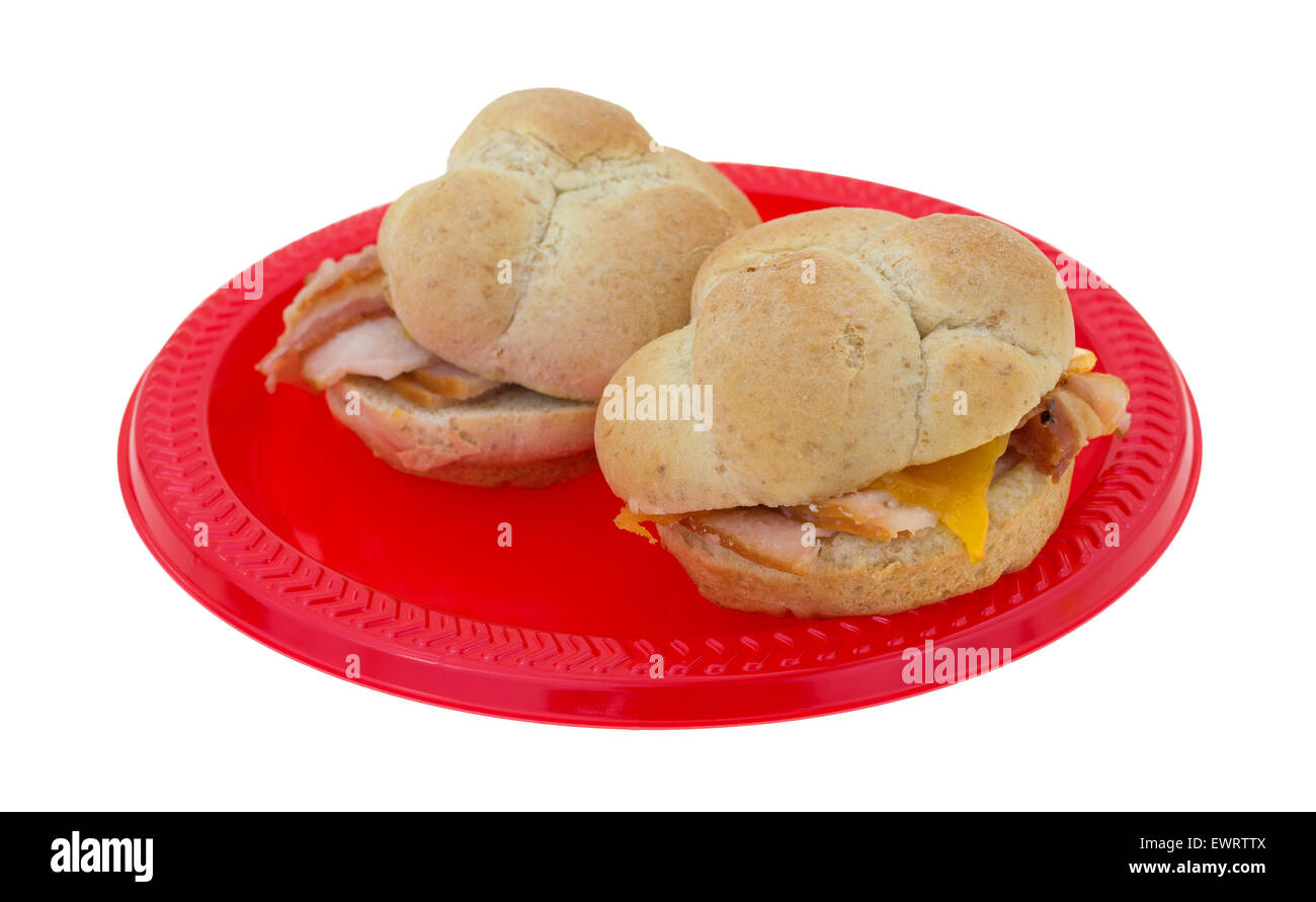 Zwei kleine Truthahn-Sandwiches mit Speck und Cheddar Käse auf Weizen Brötchen auf einem roten Picknick Teller. Stockfoto