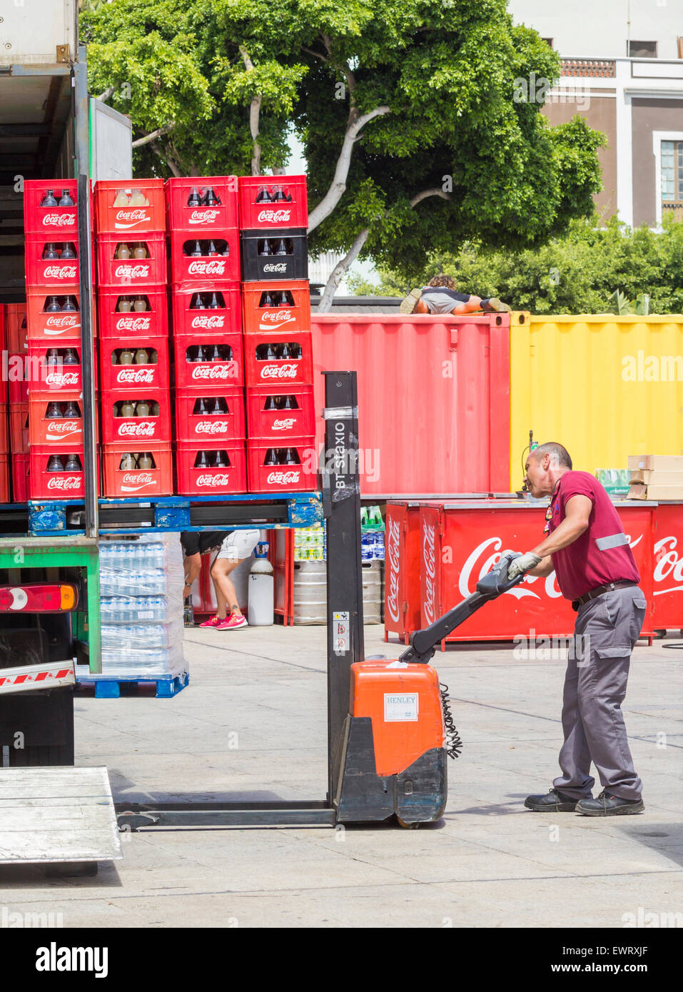 Lieferung-Treiber entladen Palette von Coca Cola mit Hand betriebenen Gabelstapler. Stockfoto