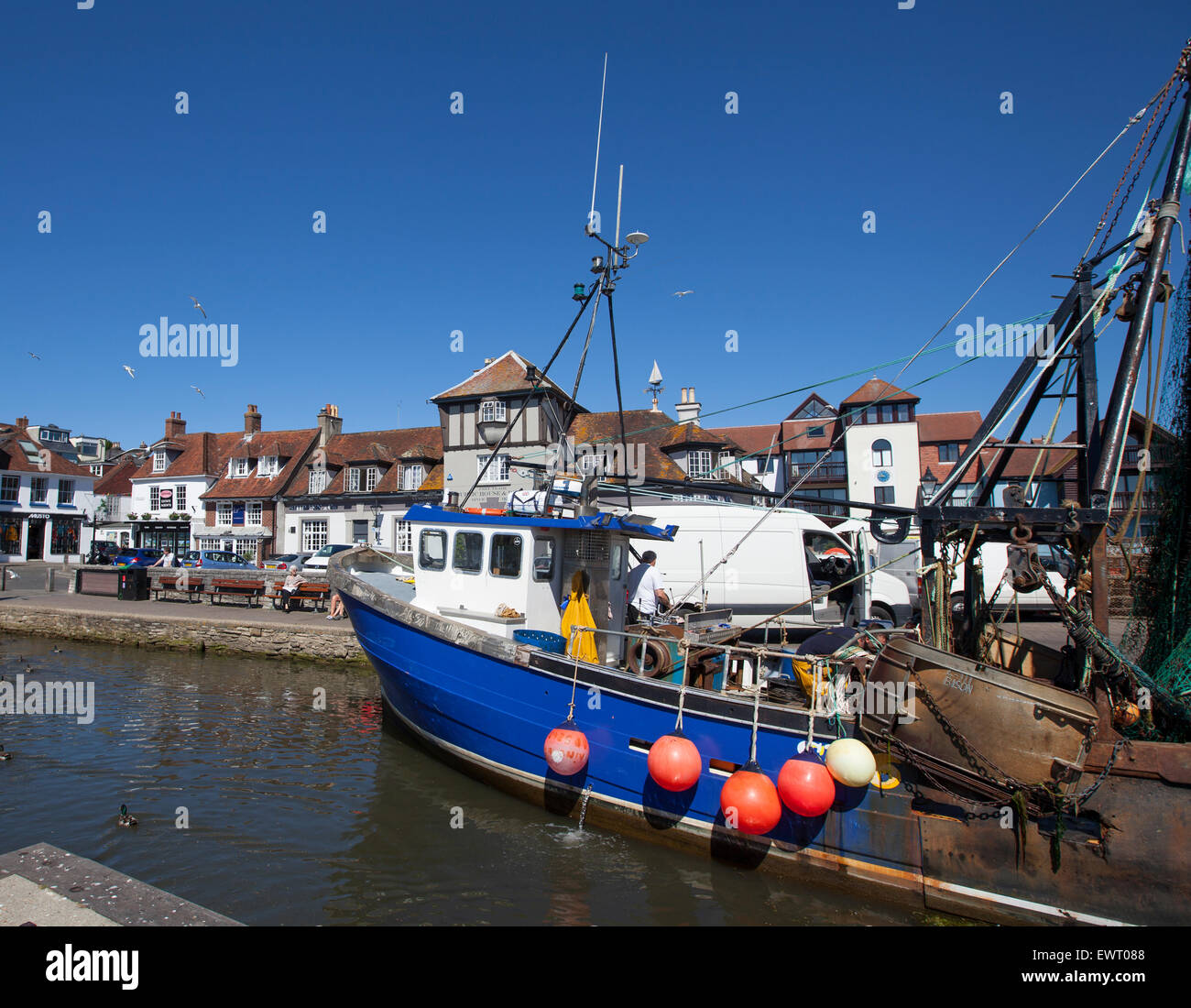 Fischkutter in Lymington Quay mit Geschäften und Restaurants im Hintergrund abgebildet Stockfoto