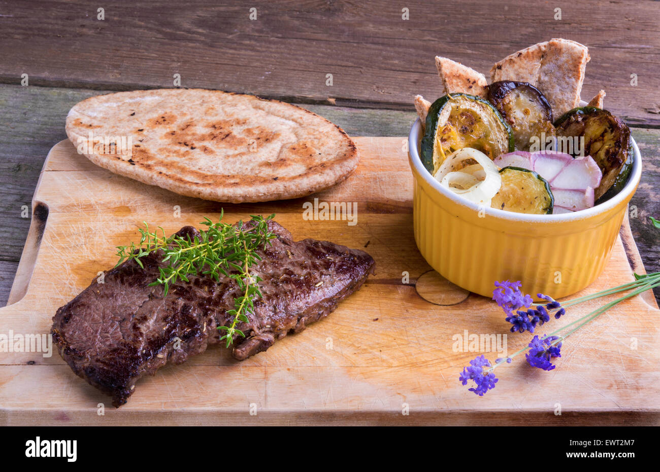 Provenzalischen Stil Pferd Fleisch Entrecote Steak mit Ratatouille und Fladenbrot serviert auf einem Holzbrett, dekoriert mit Lavendel und Stockfoto