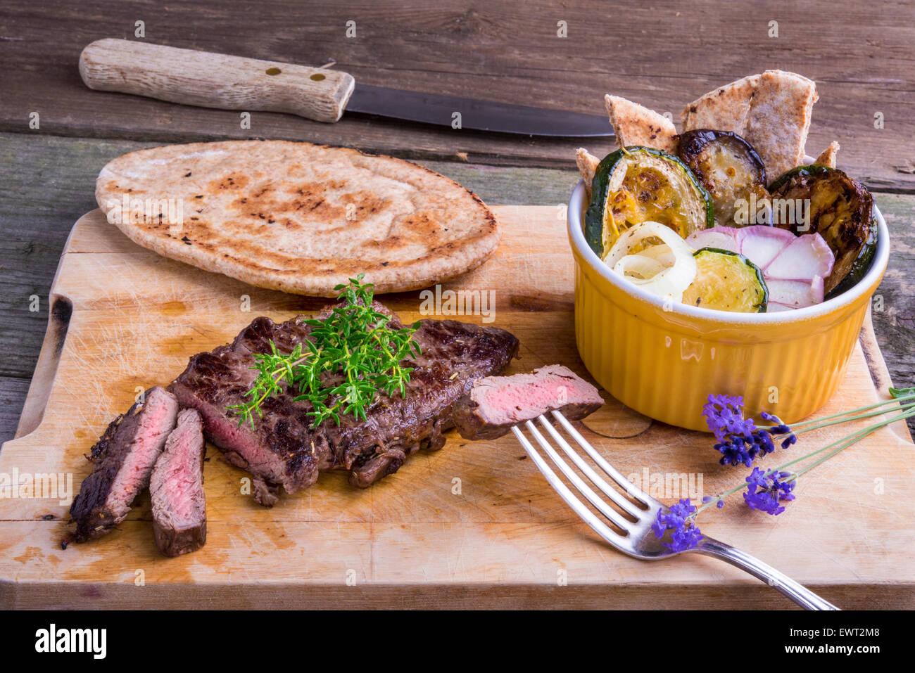 Provenzalischen Stil Pferd Fleisch Entrecote Steak mit Ratatouille und Fladenbrot serviert auf einem Holzbrett, dekoriert mit Lavendel und Stockfoto