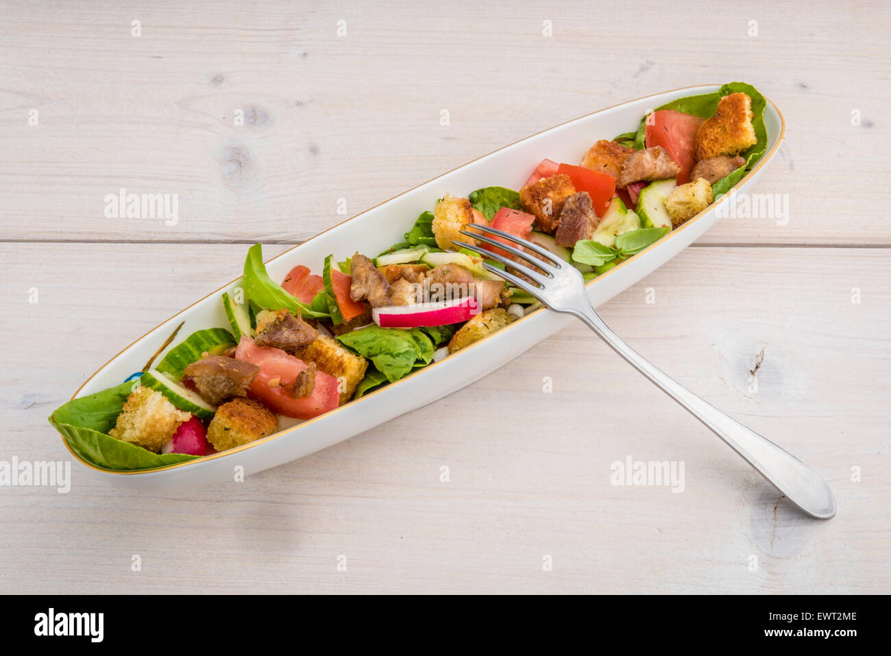 Frischer Salat mit Chinakohl, Tomaten, Radiches, Gurke, Basilikum, Croutons und gegrilltem Putenfleisch. Stockfoto