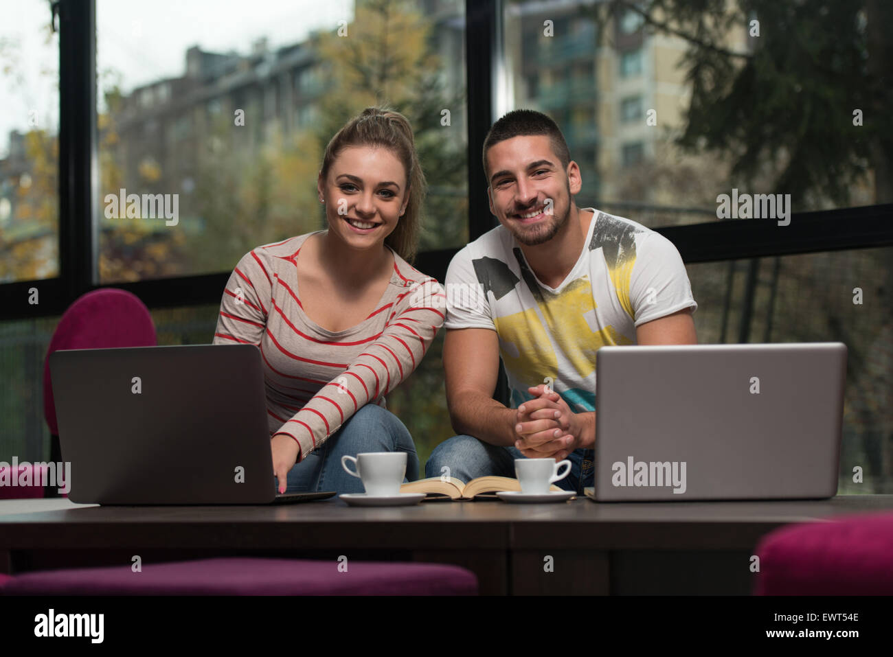 Zwei schöne Studenten trinken und Spaß mit Laptop In Cafeteria Stockfoto