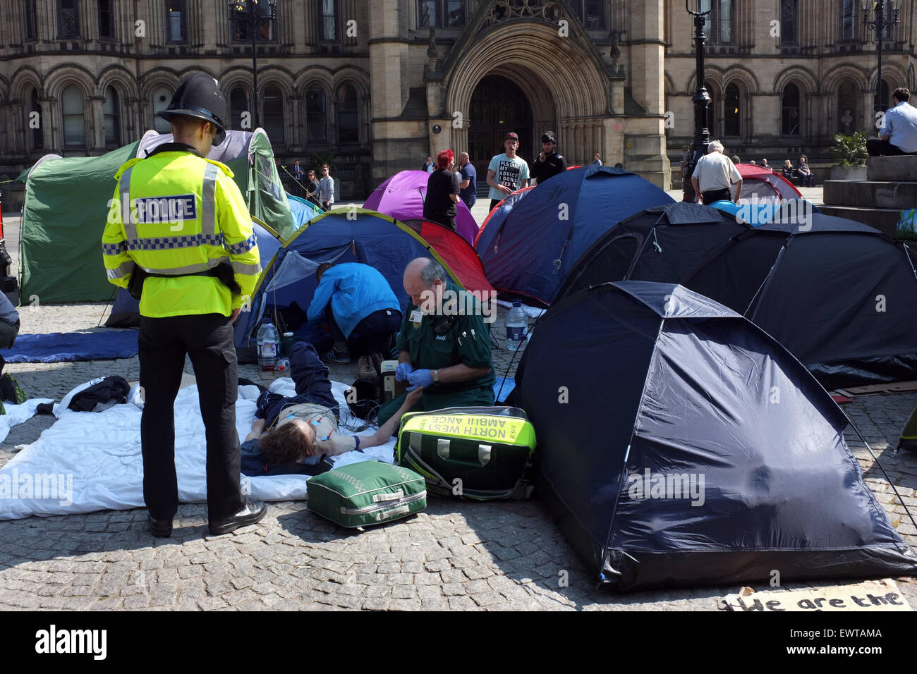Ein Sanitäter und Polizisten helfen einem Obdachlosen Demonstranten camping in Albert Square Manchester England Grossbritannien 2015 Stockfoto