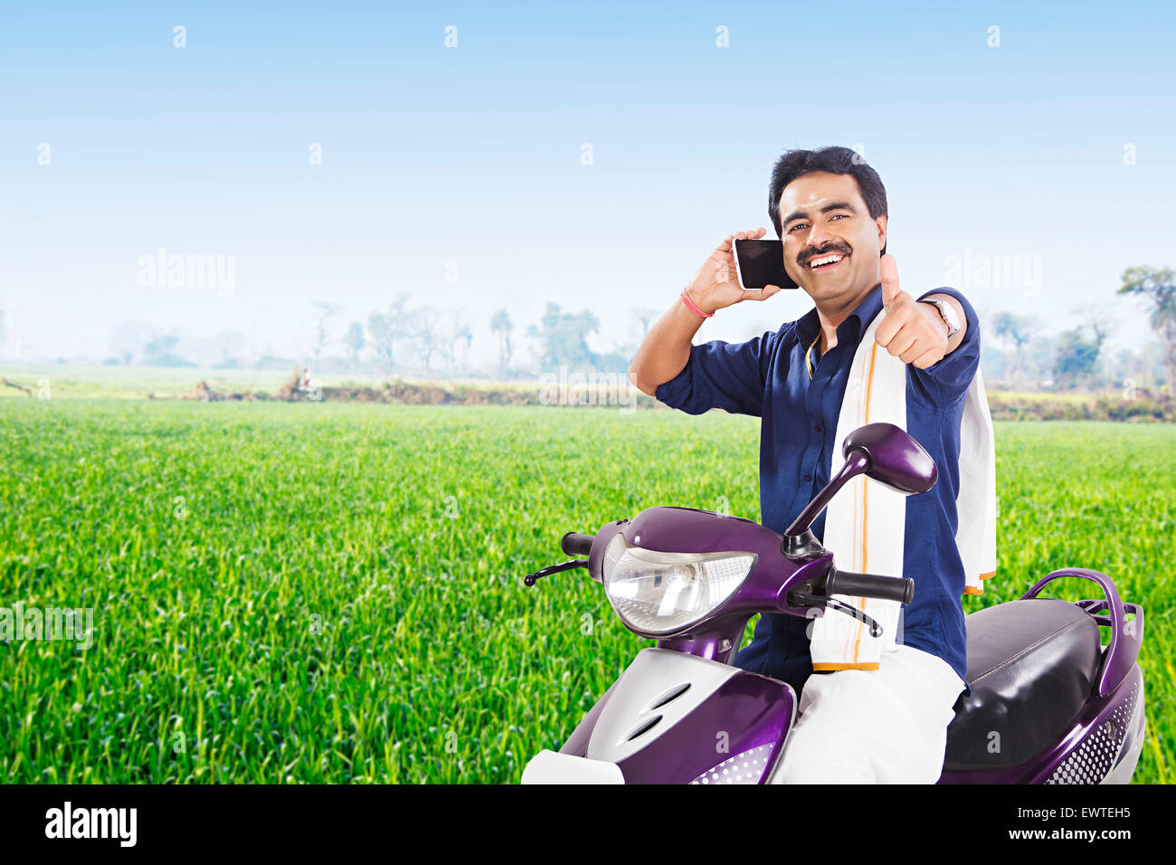 1 South Indian Mann auf dem Bauernhof Reiten Scooty und Handy im Gespräch Stockfoto