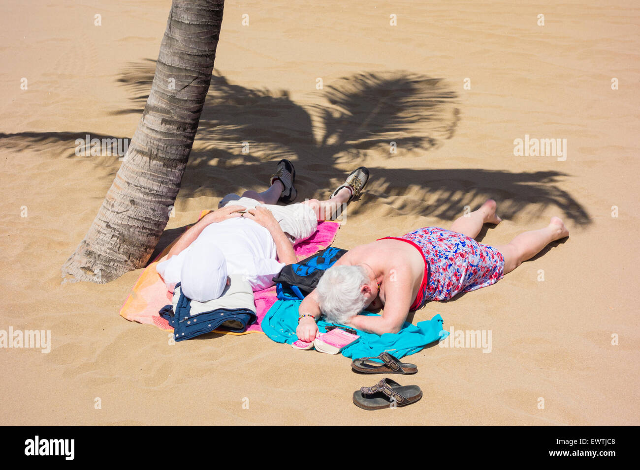Älteres paar unter Palmen am Strand Stockfoto