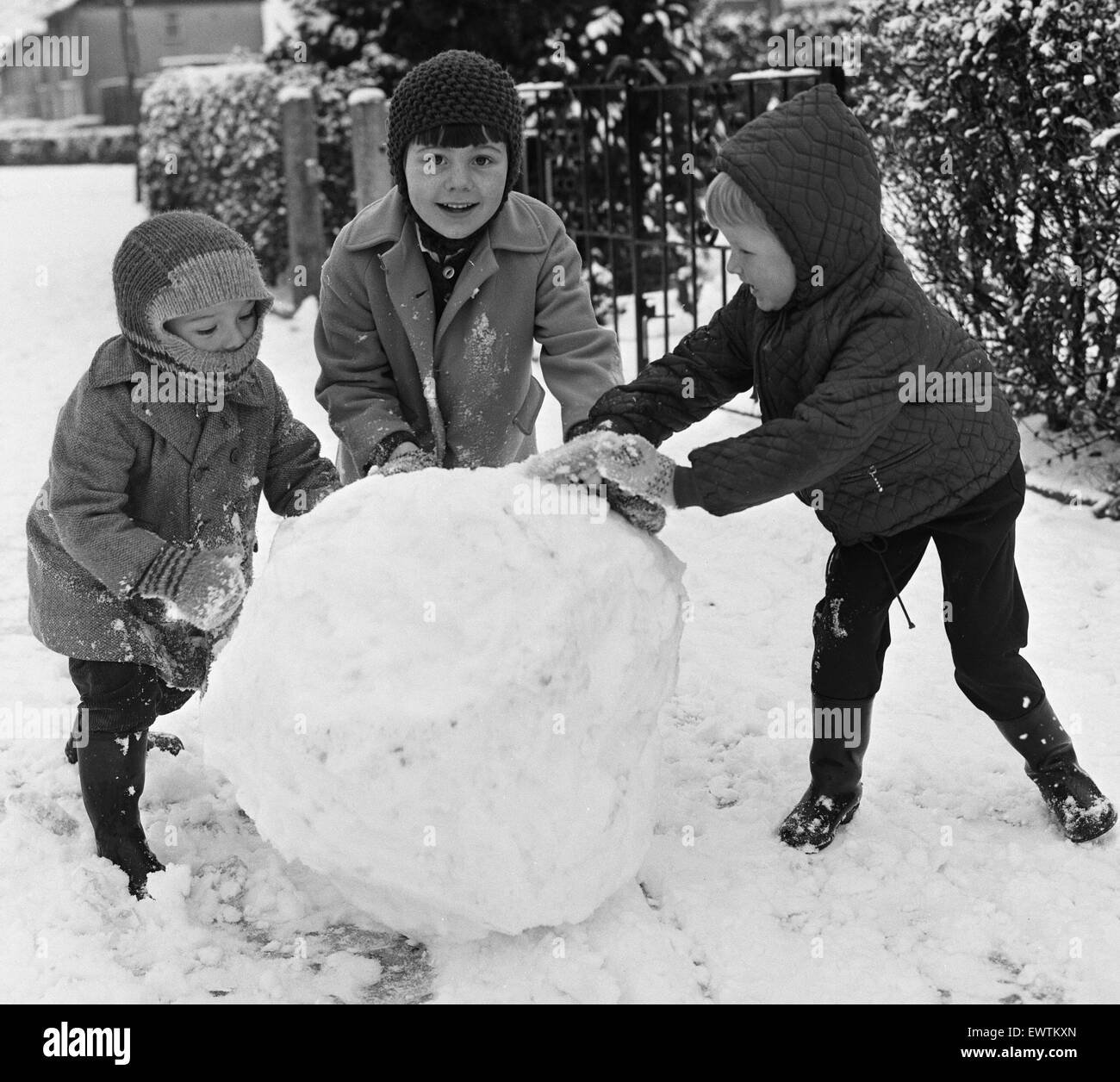 Möchten Sie einen Schneemann zu bauen? Drei Kinder, die hier in Reading gesehen profitieren Sie von den schweren Schnee fallen, einen Schneemann zu bauen. Ca. Januar 1968 Stockfoto