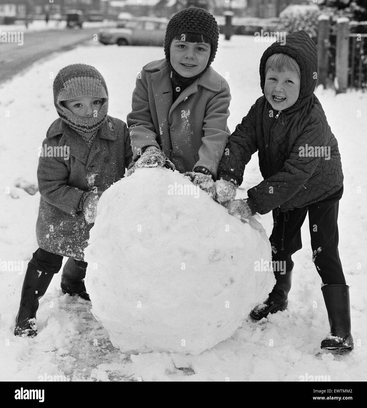 Möchten Sie einen Schneemann zu bauen? Drei Kinder, die hier in Reading gesehen profitieren Sie von den schweren Schnee fallen, einen Schneemann zu bauen. Ca. Januar 1968 Stockfoto