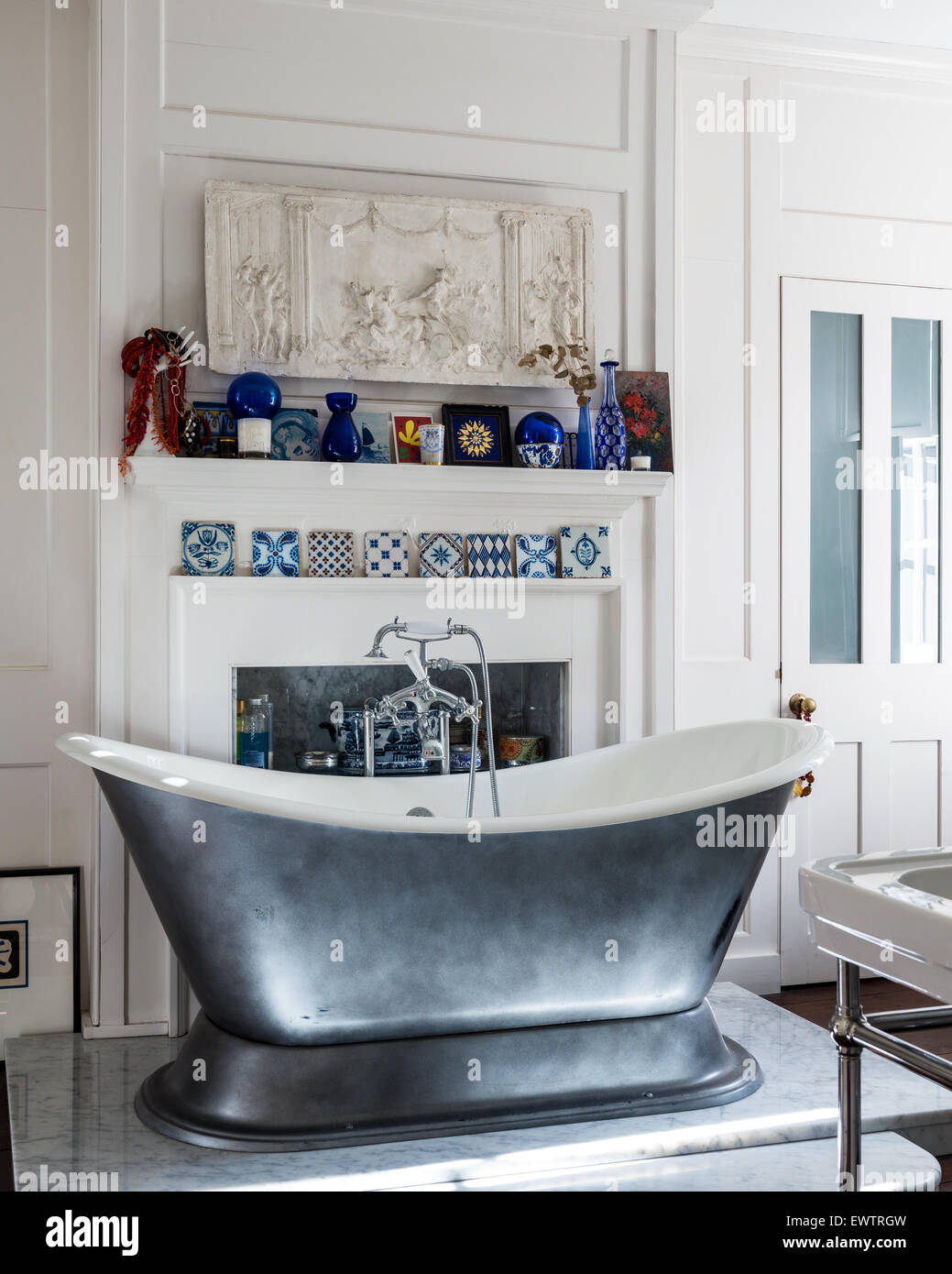Blaue und weiße Dekorfliesen auf Kaminsims im Badezimmer mit Roll Top Badewanne von Albion Bäder Stockfoto