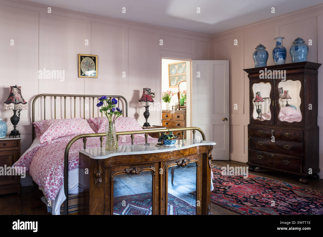 Aus Marmor gekrönt Chiffonier am Fuße des 19. Jahrhunderts-Messing-Bett im Schlafzimmer mit persischen Läufer und Spiegel-fronted Schrank Stockfoto