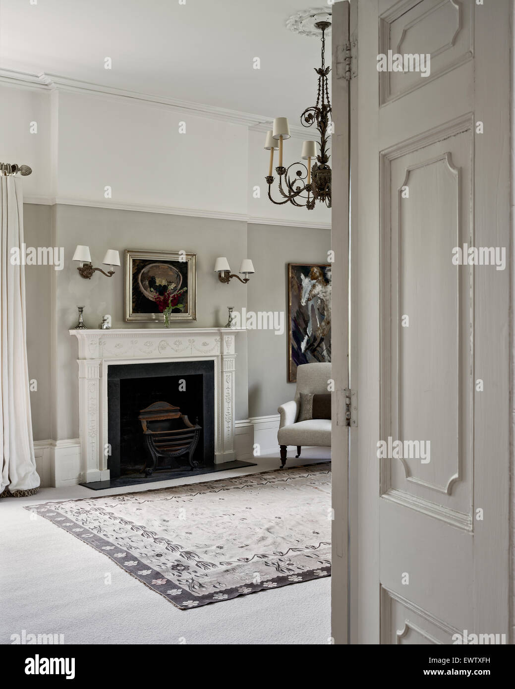 Blick durch eine getäfelte Tür in eleganten Schlafzimmer gemalt in Pale Nussbaum von Dulux mit Aubusson Teppich und Kamin Stockfoto