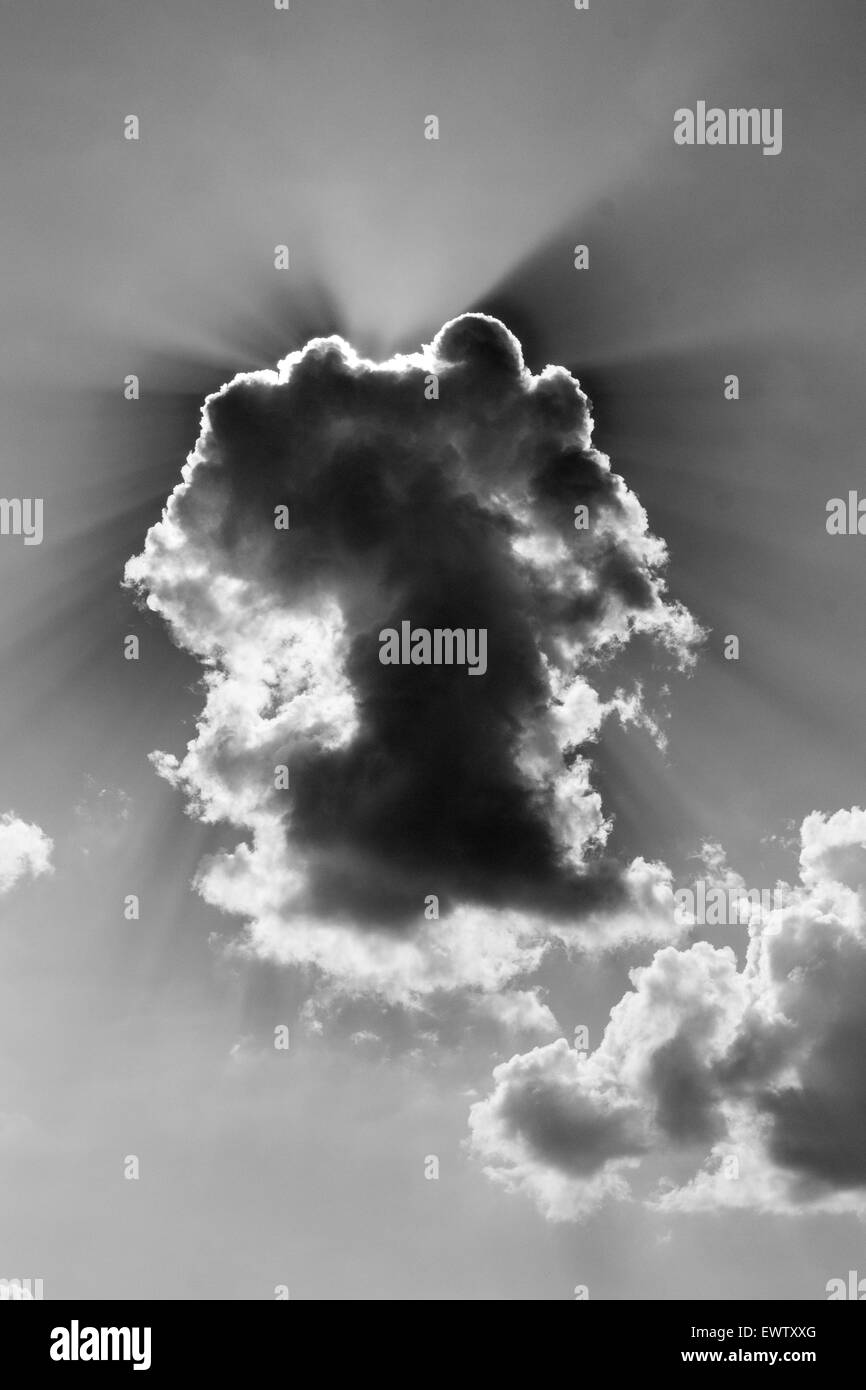 Sommer Wolkenbildung mit Sonnenstrahlen und dunkle Bereiche mit blauem Himmel in schwarz / weiß Stockfoto