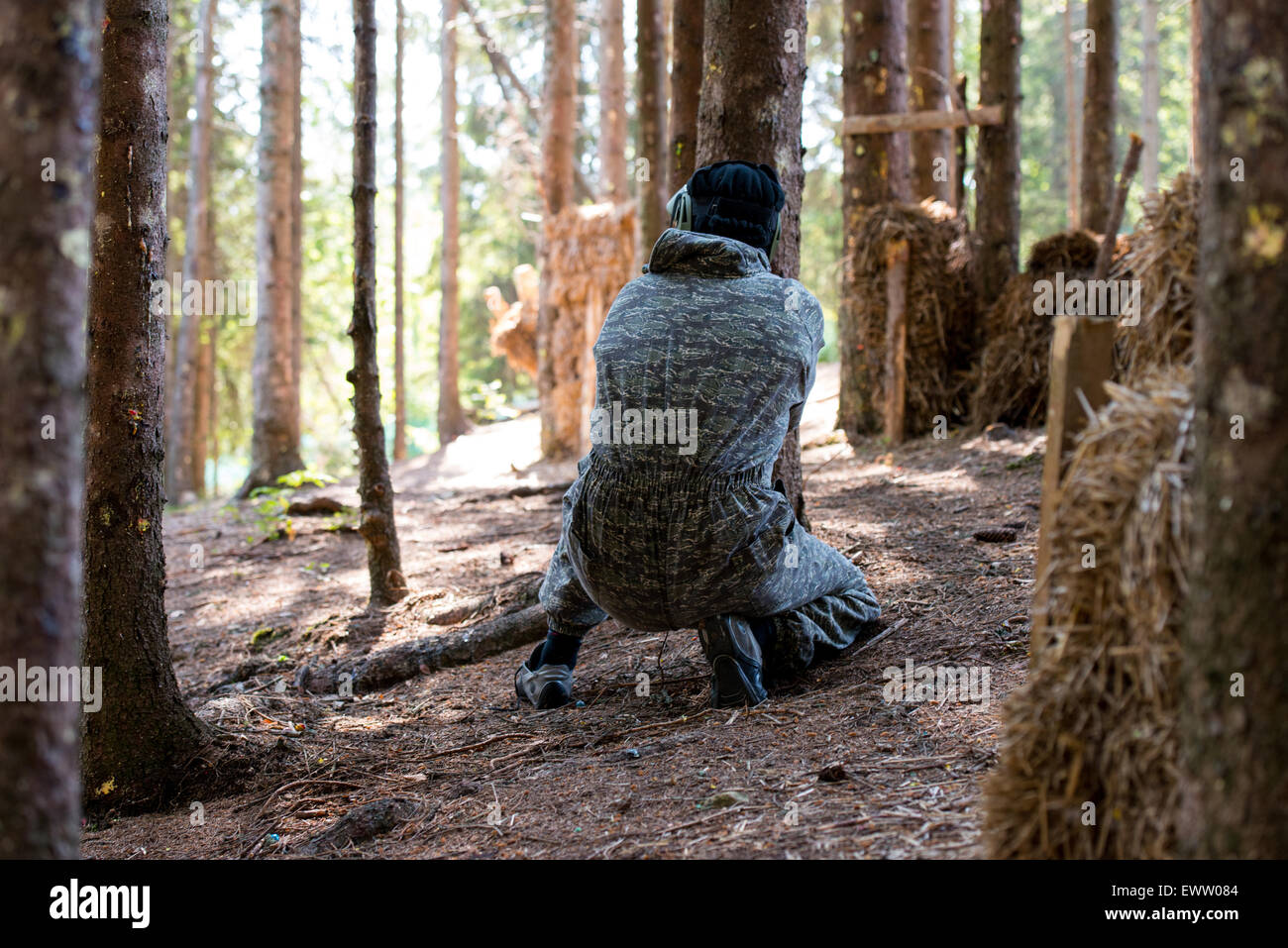 Paintball-Spieler verstecken sich hinter Baum Stockfoto