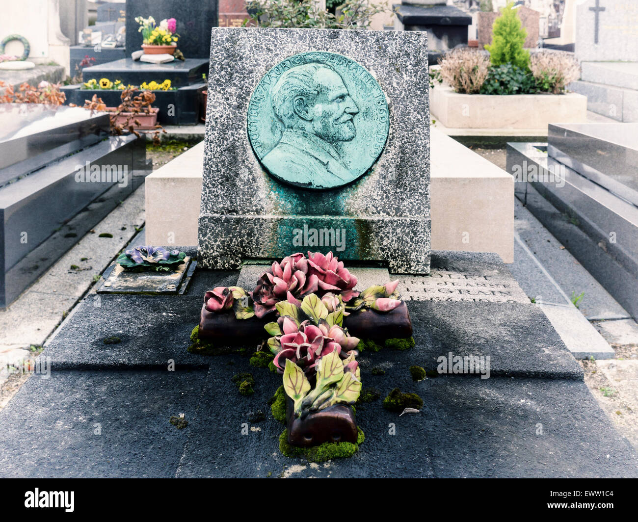 Cimetière du Montparnasse, Paris Montparnasse Friedhof Grab Detail, Grabstein mit grünen Medaillon, Porzellan Blumen, Kreuz Stockfoto