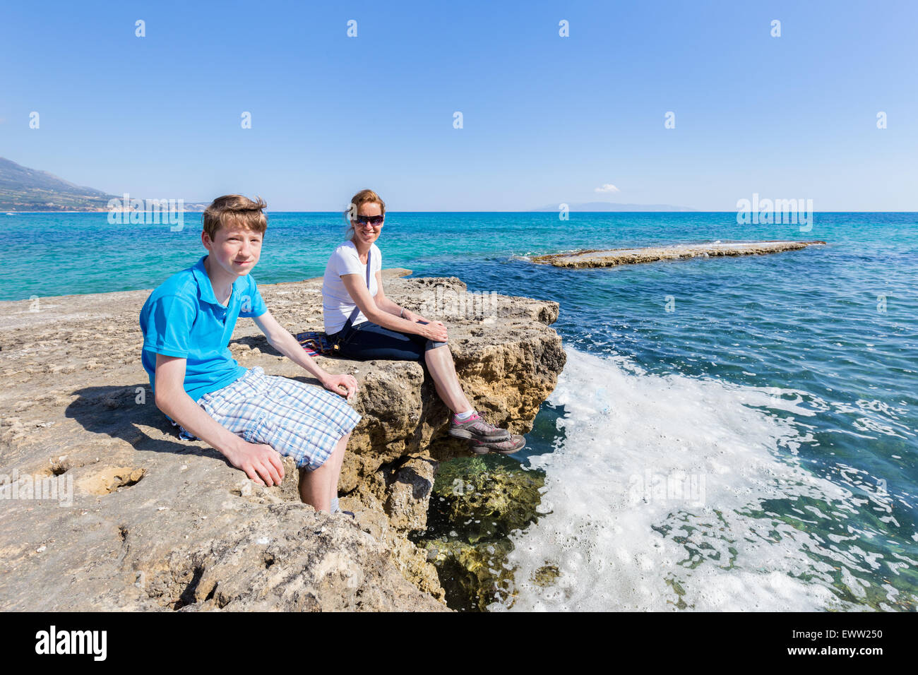 Mutter und Sohn als Touristen sitzen auf Felsen am Meer Urlaub genießen Stockfoto