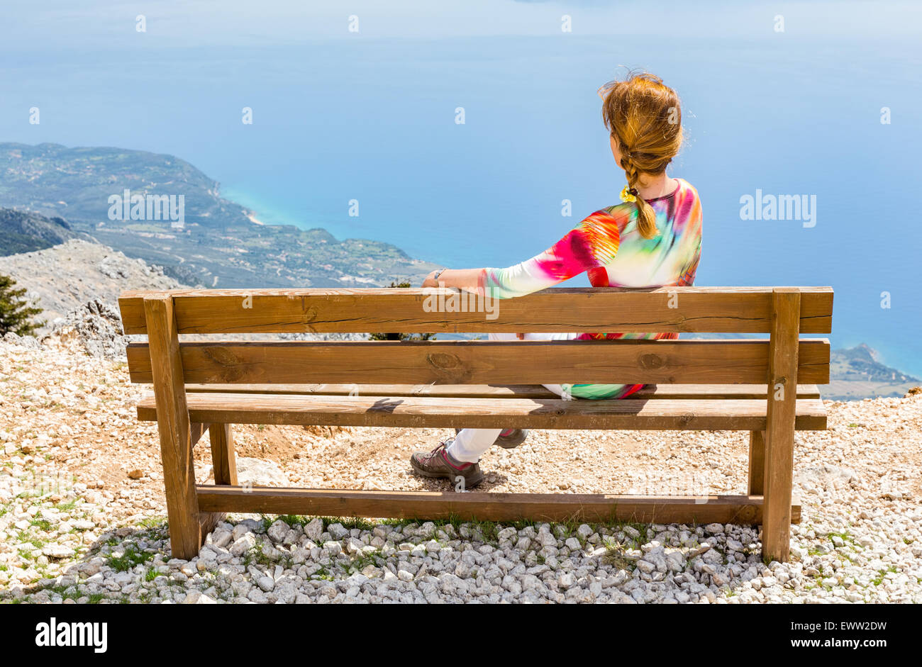 Applying Frau sitzt auf braune Holzbank auf Berg genießen Urlaub in Griechenland Stockfoto