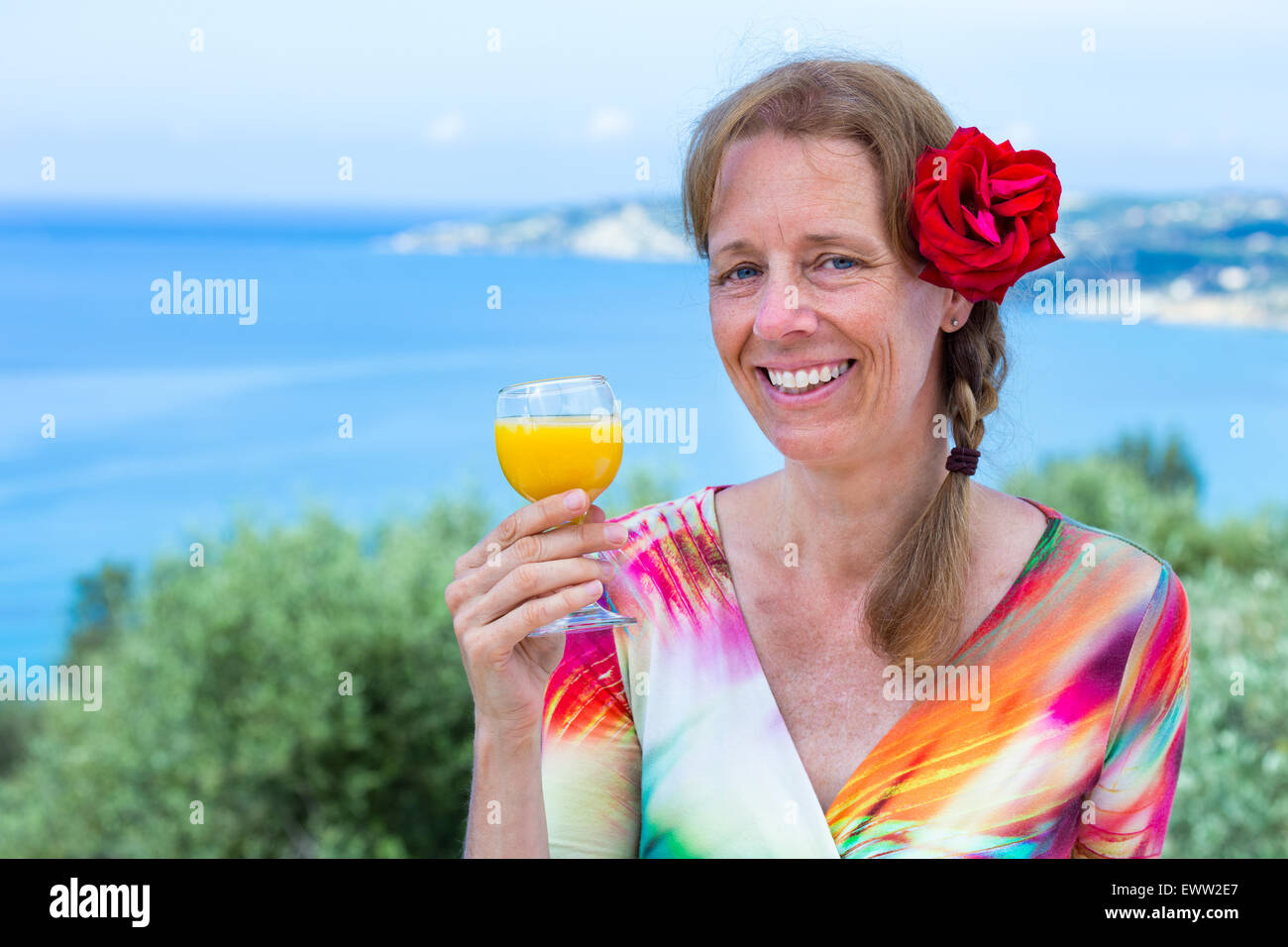 Mittleren Alter Europäerin mit roter rose Holding Getränk in der Nähe von Meer in den Urlaub Stockfoto