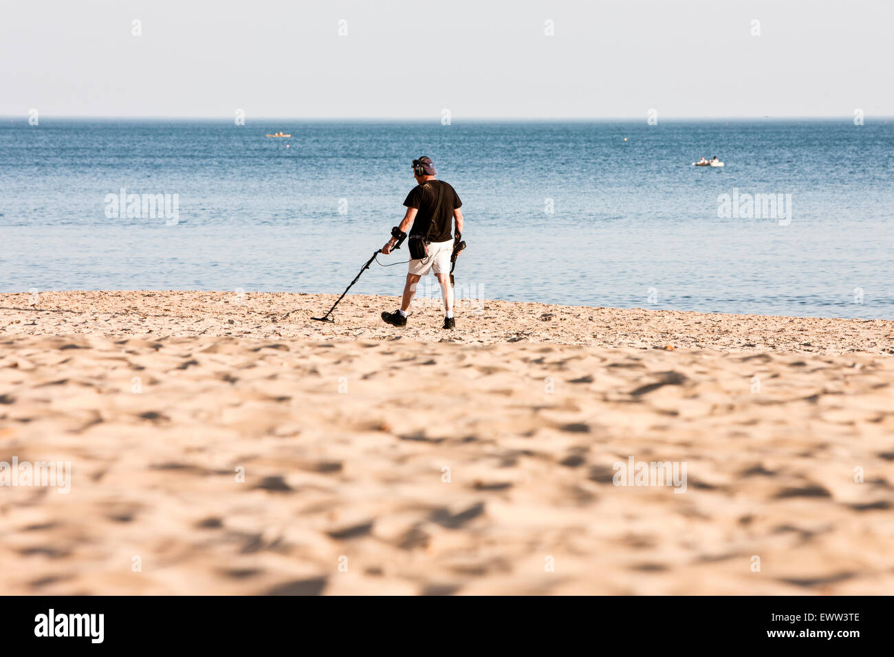 An einem sonnigen Frühlingstag, ein Detectorist mit Metalldetektor nach den meisten Touristen/Urlauber verlassen haben Strand auf der Suche nach verlorenen Gegenständen/Schatz Stockfoto