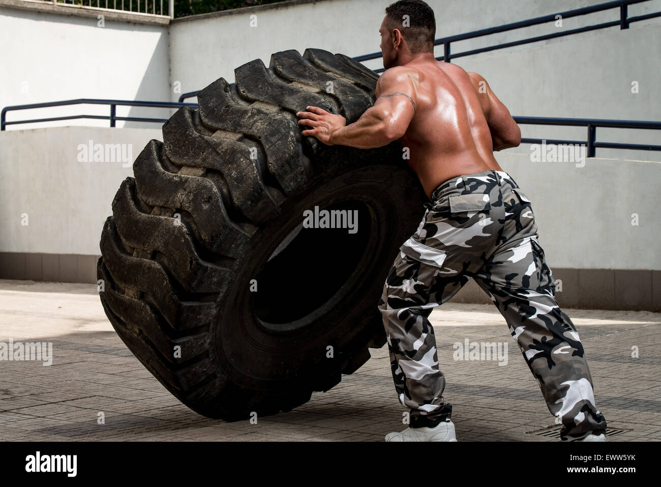 Ein muskulöser Mann, die Teilnahme an einem Kreuz fit Training auf diese Weise einen Reifen-flip Stockfoto