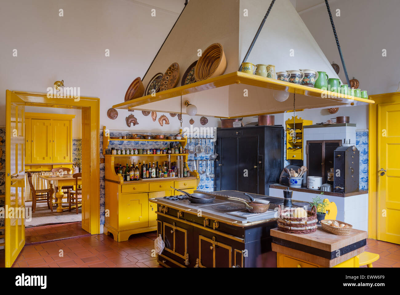 Helle Küche mit Türen, Küchenherd, gelbe Kommode und Delfter Kacheln Stockfoto