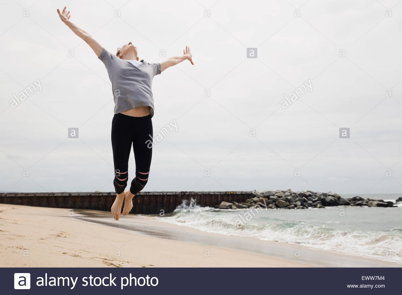 Üppige Frau springen vor Freude am Strand Stockfoto