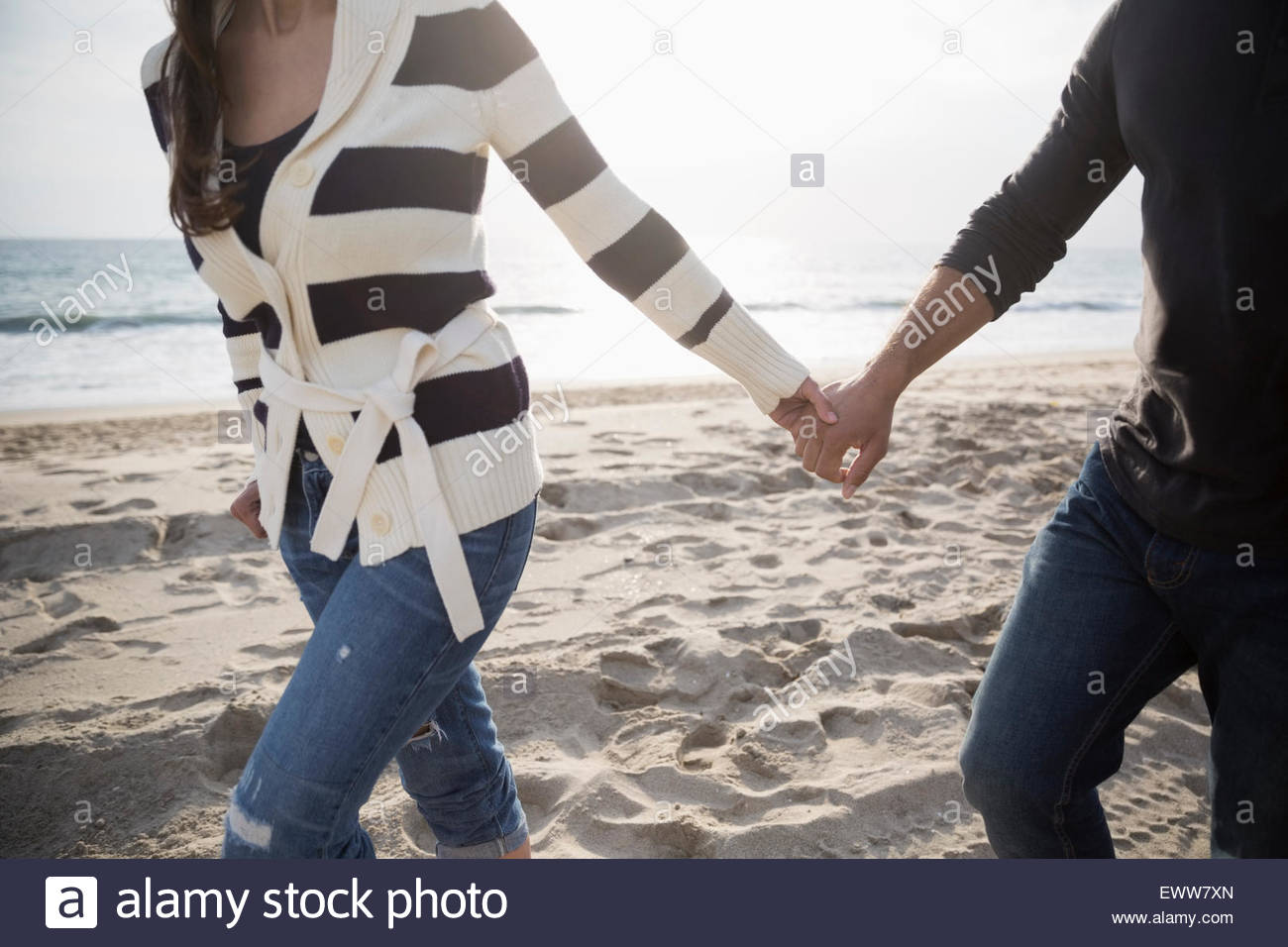 Paar Hände halten und zu Fuß am Strand. Stockfoto