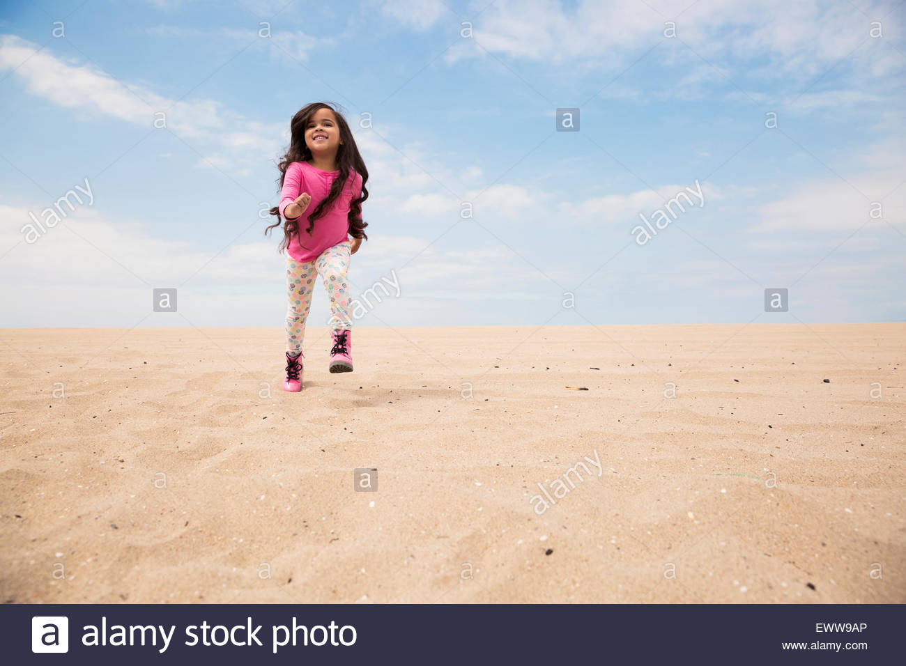 Lächelnde Mädchen lange Haare laufen am Strand Hang Stockfoto