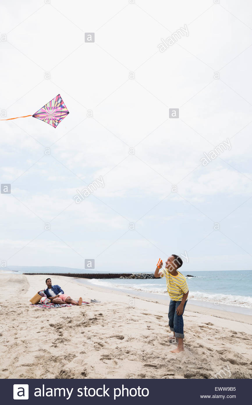 Vater und Sohn fliegen Kite am Strand Stockfoto