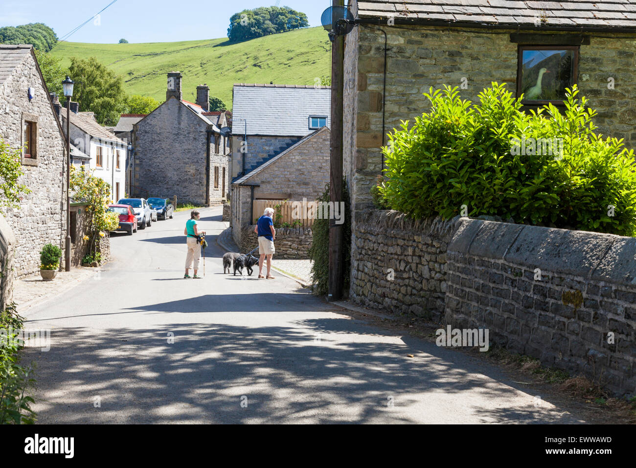 Leute, die ihre Hunde an einer ruhigen Dorfstraße im Sommer. Castleton, Derbyshire, Peak District National Park, England, Großbritannien Stockfoto