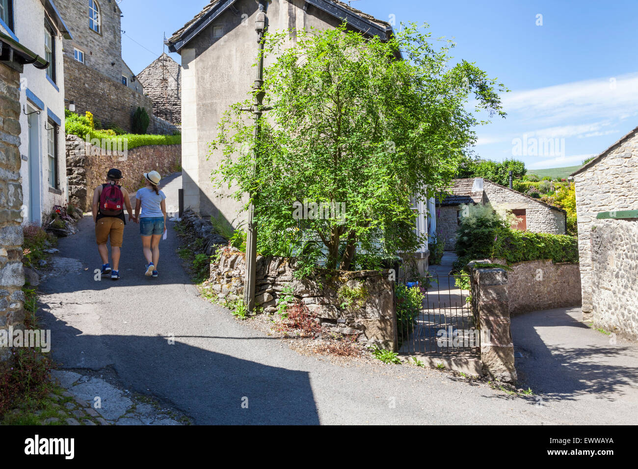 Zwei junge Menschen zu Fuß durch die engen Gassen des Peak District Dorf im Sommer. Castleton, Derbyshire, England, Großbritannien Stockfoto