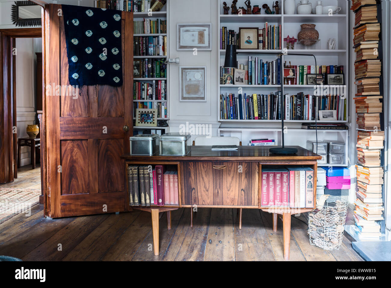 Mitte Jahrhundert Schreibtisch im home-Office mit altem Holzboden, eingebaute Regale und gestapelte Bücher Stockfoto